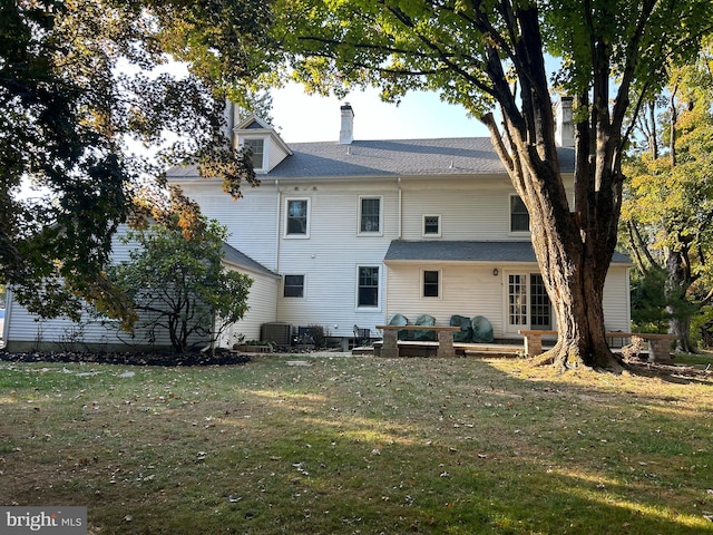 rear view of house with central AC and a yard