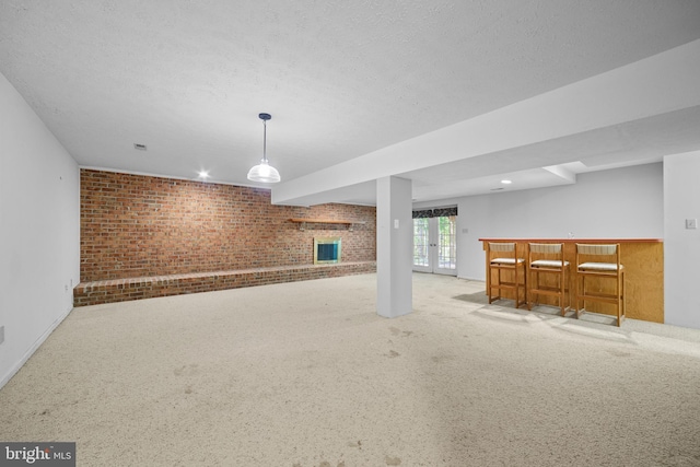 basement featuring brick wall, a textured ceiling, and light carpet