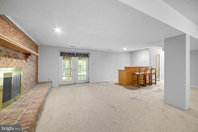 unfurnished living room with a brick fireplace, carpet floors, bar, and a textured ceiling