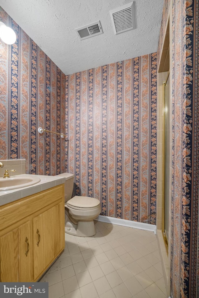 bathroom featuring a textured ceiling, walk in shower, vanity, and toilet