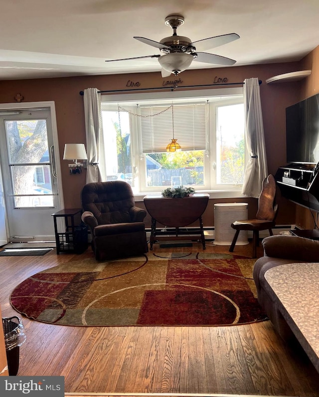 living room with ceiling fan, wood-type flooring, and baseboard heating