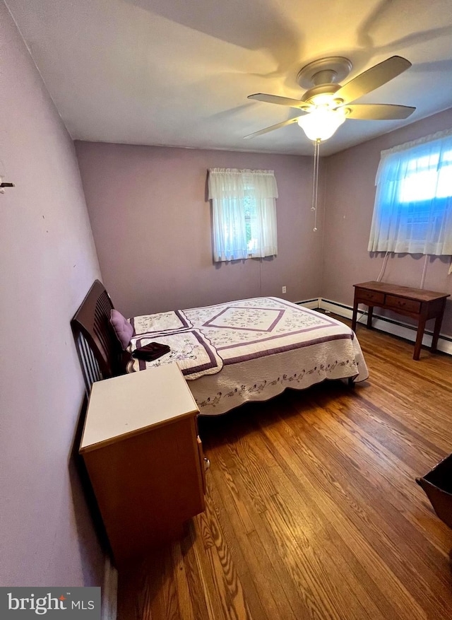 bedroom featuring multiple windows, hardwood / wood-style flooring, and ceiling fan