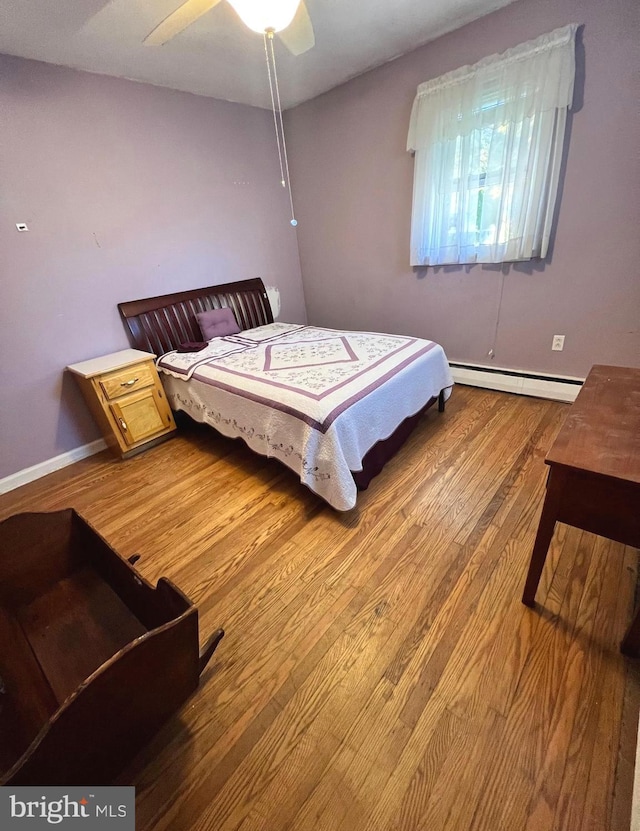 bedroom with ceiling fan, baseboard heating, and hardwood / wood-style floors