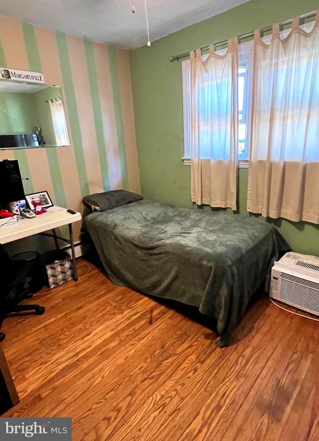 bedroom featuring hardwood / wood-style floors and an AC wall unit