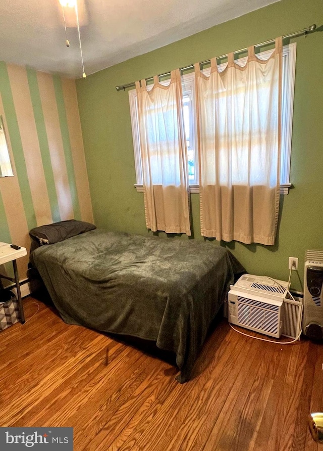 bedroom with wood-type flooring and a wall unit AC