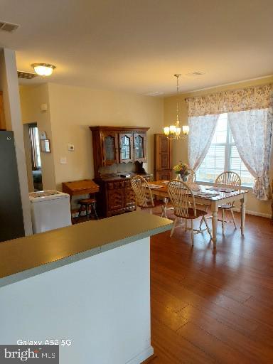 kitchen with dark hardwood / wood-style flooring, black fridge, decorative light fixtures, and a notable chandelier