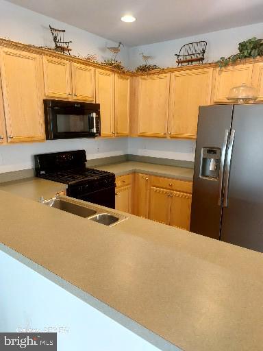 kitchen with light brown cabinets, sink, black appliances, and kitchen peninsula