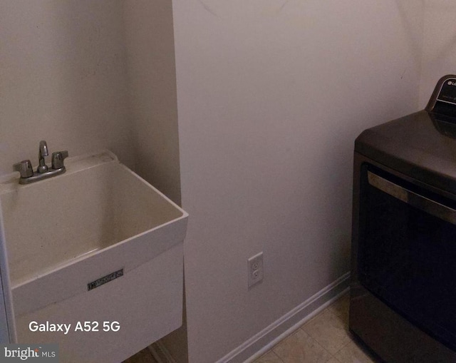 clothes washing area featuring washer / clothes dryer and sink