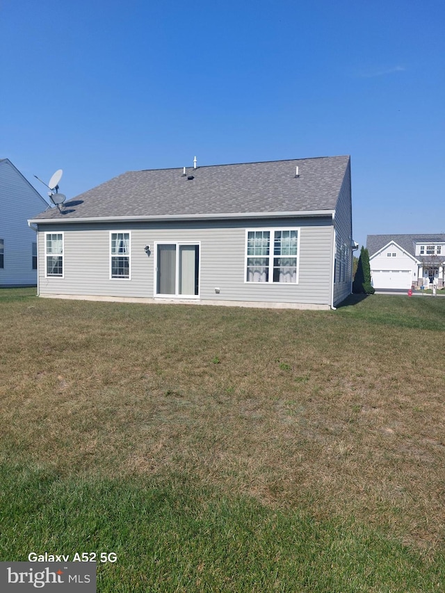 rear view of house featuring a garage and a yard