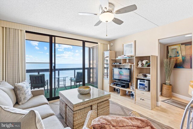 living room with light hardwood / wood-style floors, a textured ceiling, and ceiling fan