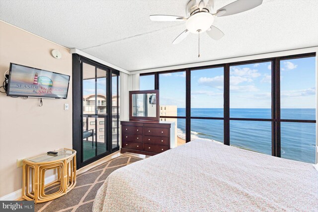 bedroom with expansive windows, multiple windows, a water view, and ceiling fan