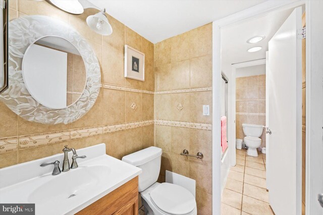 bathroom featuring vanity, tile walls, toilet, and tile patterned flooring