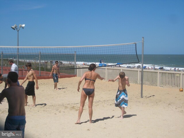 view of property's community with volleyball court, a water view, and a view of the beach