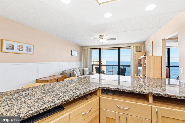 kitchen featuring built in desk, light brown cabinetry, a water view, and ceiling fan