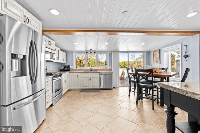kitchen with wood ceiling, beamed ceiling, a sink, stainless steel appliances, and light countertops