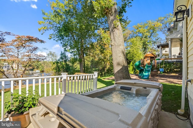 view of patio / terrace with a playground, a water view, and a hot tub