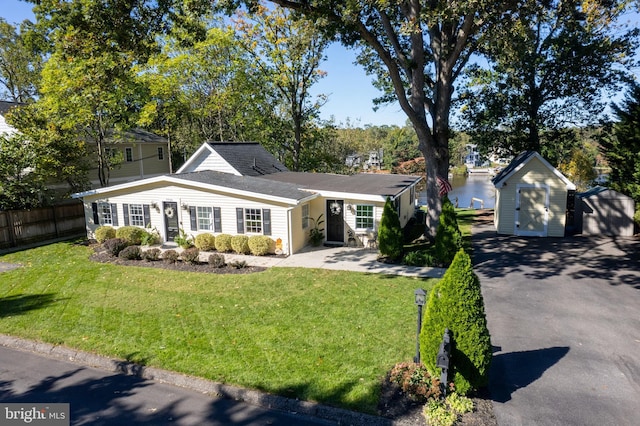 view of front of property featuring a storage unit, a detached garage, an outbuilding, a front yard, and fence