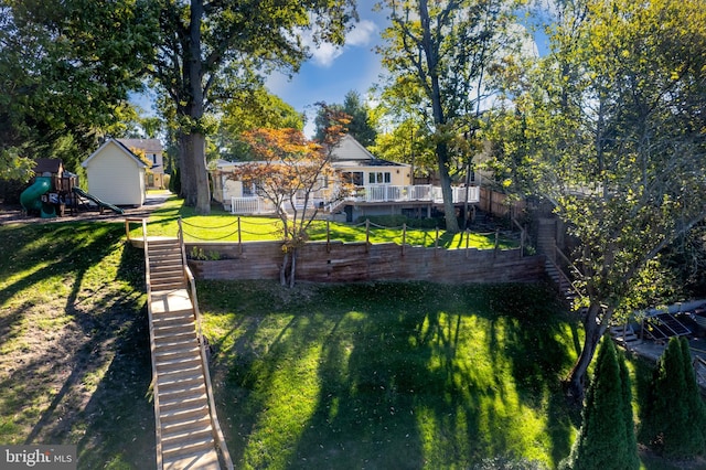 rear view of house with a lawn, a playground, stairway, and fence