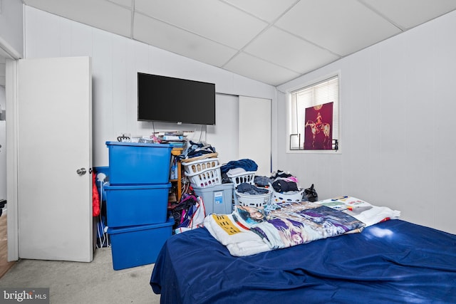 carpeted bedroom featuring a drop ceiling and a closet