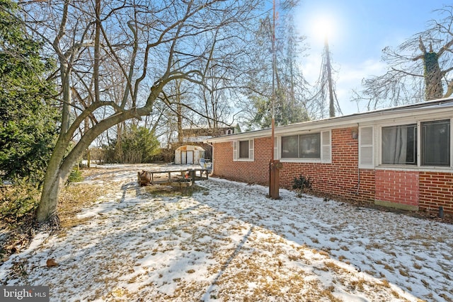 view of snowy exterior with a storage shed