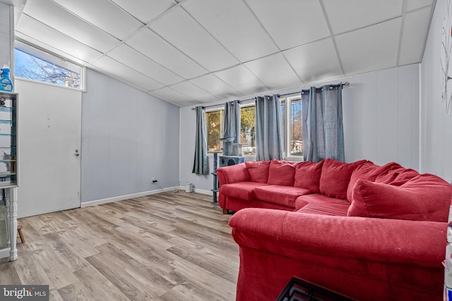 living room with a wealth of natural light, light hardwood / wood-style floors, and a drop ceiling