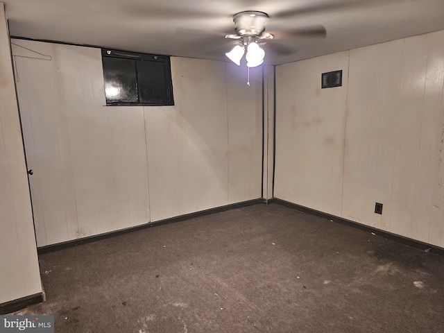 basement featuring ceiling fan and dark carpet