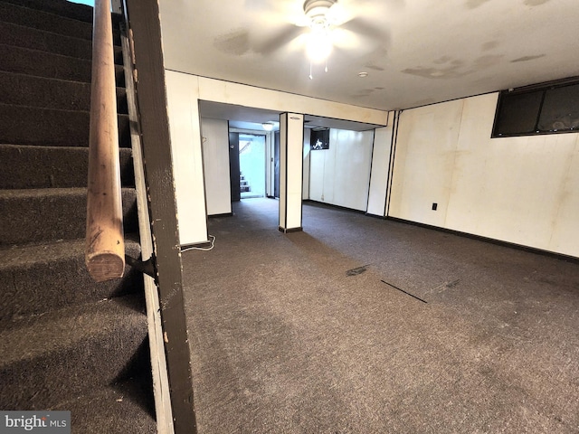 basement featuring dark colored carpet and ceiling fan