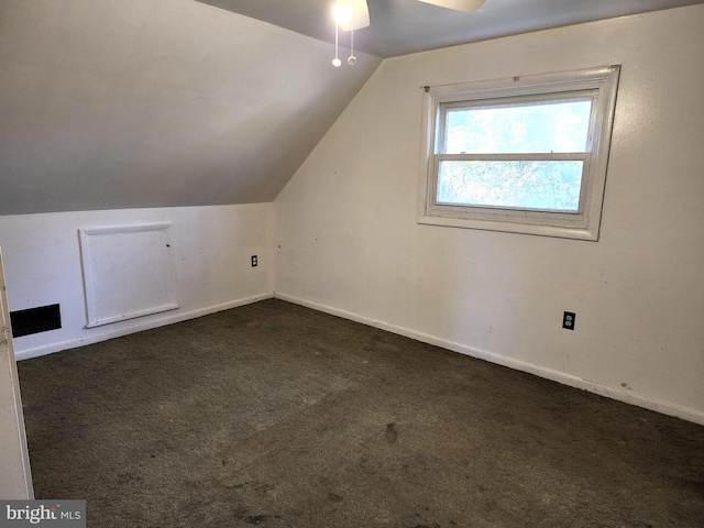 additional living space featuring ceiling fan, dark colored carpet, and lofted ceiling