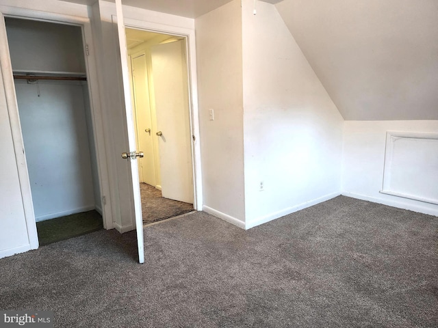 additional living space featuring lofted ceiling and dark colored carpet