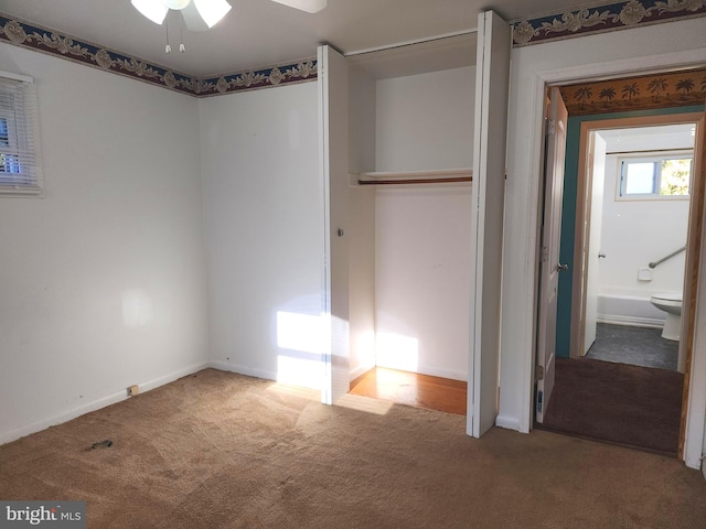 unfurnished bedroom featuring ceiling fan, ensuite bath, and carpet flooring