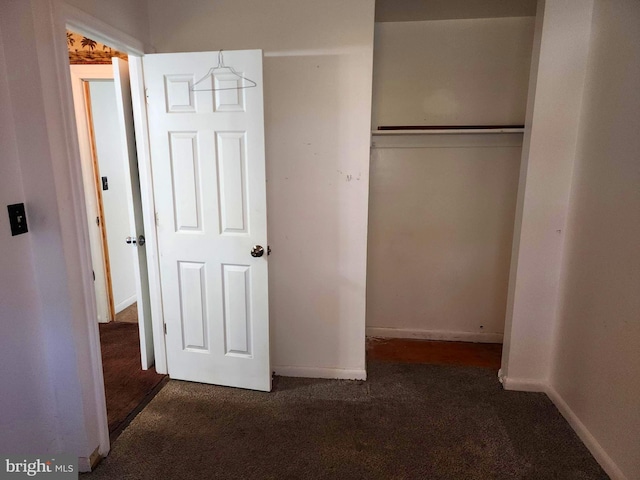 unfurnished bedroom with dark colored carpet and a closet