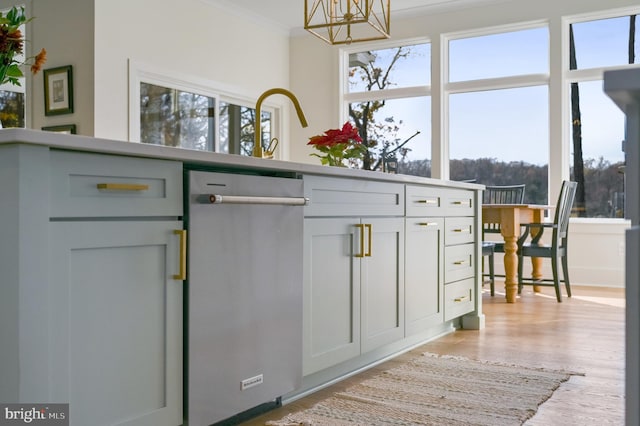 kitchen with light wood-type flooring, stainless steel dishwasher, ornamental molding, and plenty of natural light