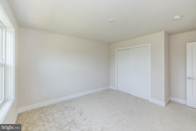 unfurnished bedroom featuring light colored carpet and a closet