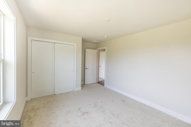 unfurnished bedroom with a closet and light colored carpet