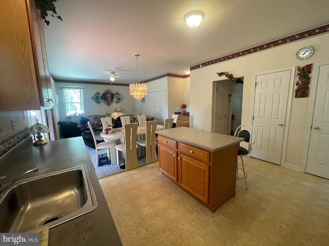 kitchen with pendant lighting, a center island, sink, ceiling fan, and a breakfast bar area