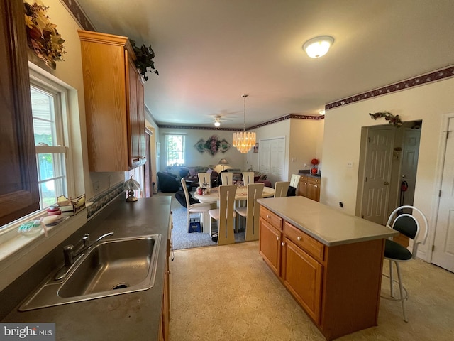 kitchen featuring a breakfast bar, ceiling fan, sink, decorative light fixtures, and a kitchen island