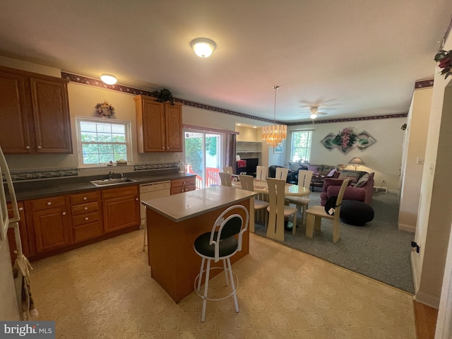 kitchen with white dishwasher, ceiling fan, a center island, and a wealth of natural light