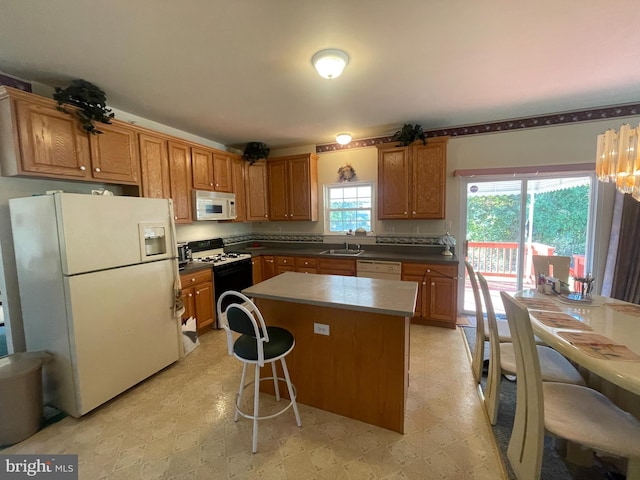 kitchen featuring a kitchen breakfast bar, white appliances, a kitchen island, and sink