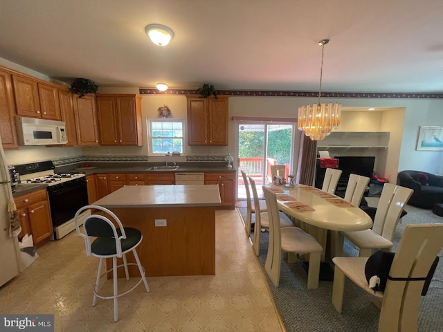 kitchen with white appliances, sink, an inviting chandelier, a center island, and hanging light fixtures