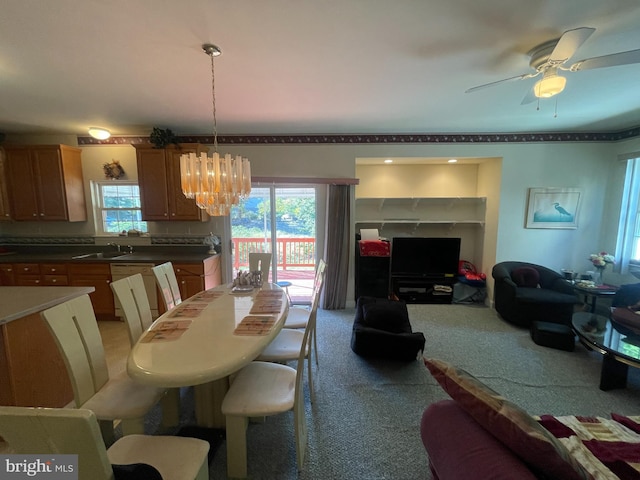 dining area featuring carpet, ceiling fan with notable chandelier, and sink