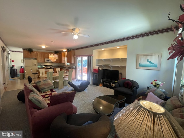 carpeted living room featuring ceiling fan with notable chandelier