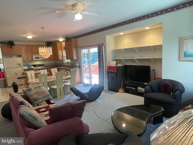 carpeted living room featuring ceiling fan with notable chandelier