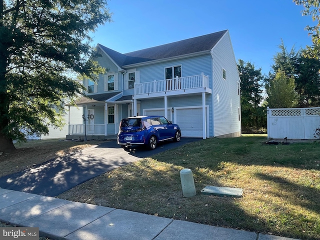 view of front facade featuring a balcony, a front lawn, and a garage