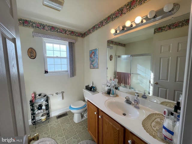 bathroom featuring tile patterned flooring, vanity, toilet, and a shower with shower door