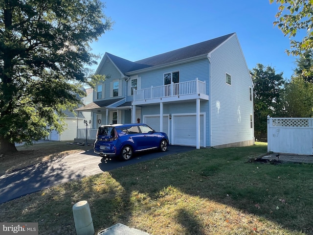 view of front of house featuring a balcony, a front yard, and a garage