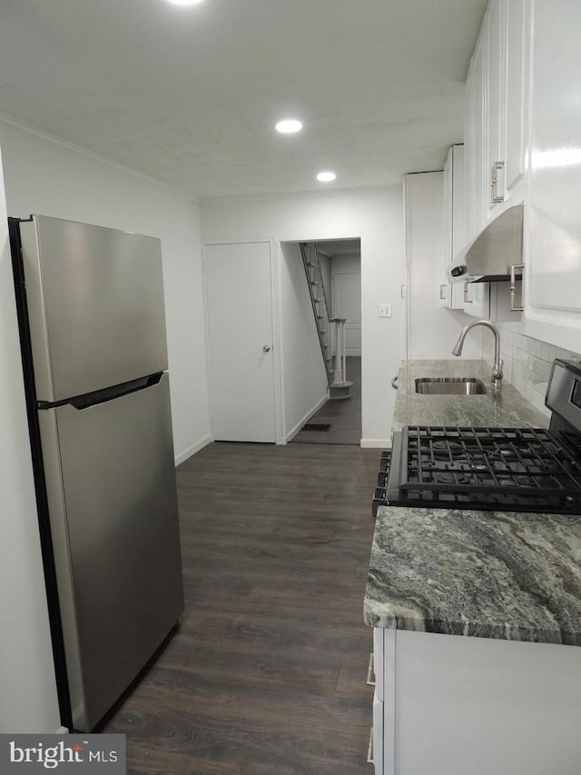 kitchen with dark wood-type flooring, stainless steel appliances, dark stone counters, sink, and white cabinets