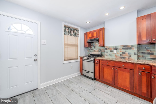 kitchen with light stone counters, stainless steel range with gas stovetop, and tasteful backsplash