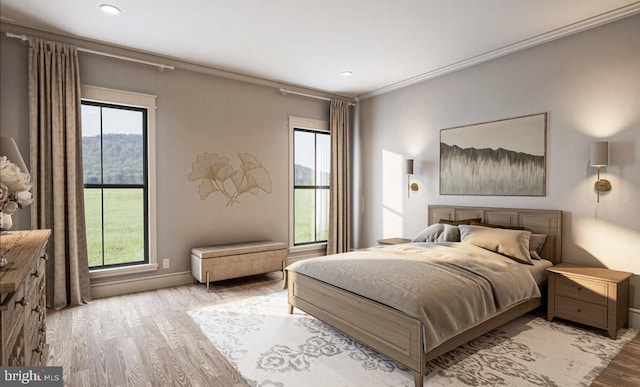 bedroom featuring ornamental molding, light wood-type flooring, and multiple windows