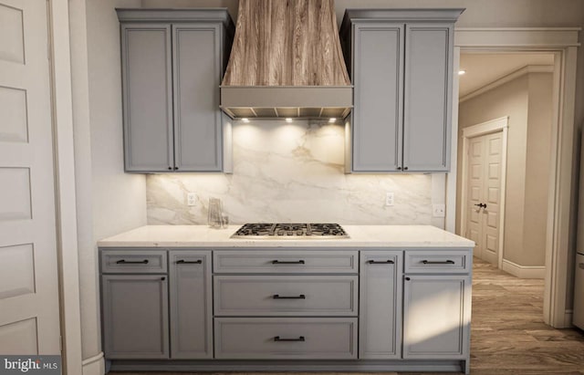 kitchen with gray cabinetry, stainless steel gas cooktop, light wood-type flooring, and custom range hood