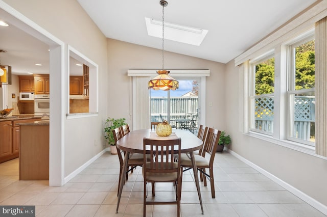 dining area featuring light tile patterned flooring and vaulted ceiling with skylight